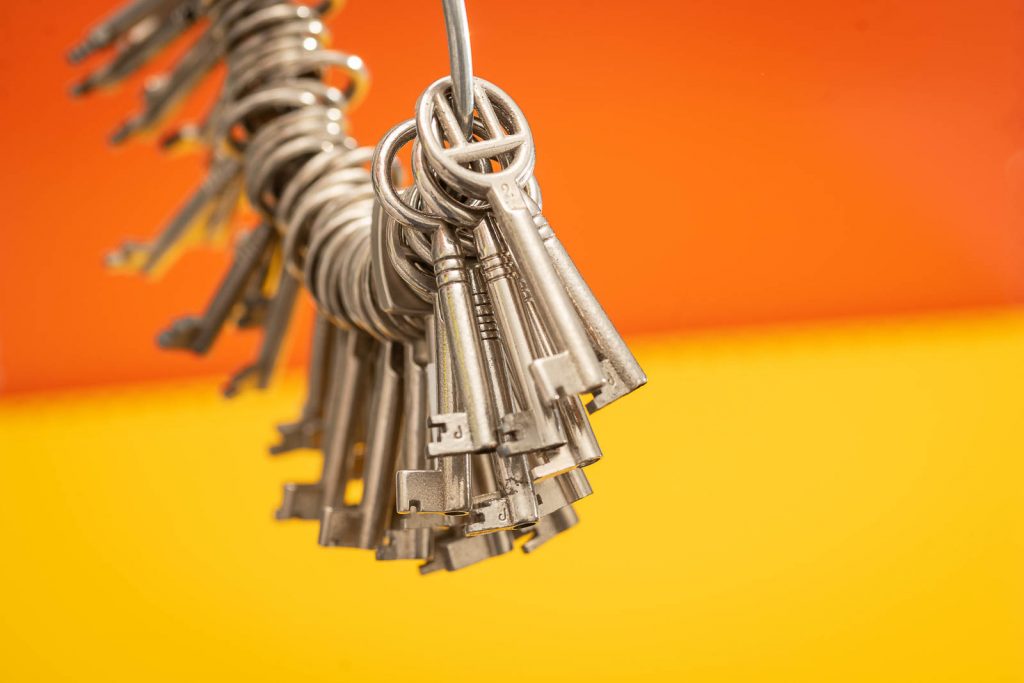 Numerierte Möbelschlüssel als Bund an einem Schlüsselring. Gelber Hintergrund.