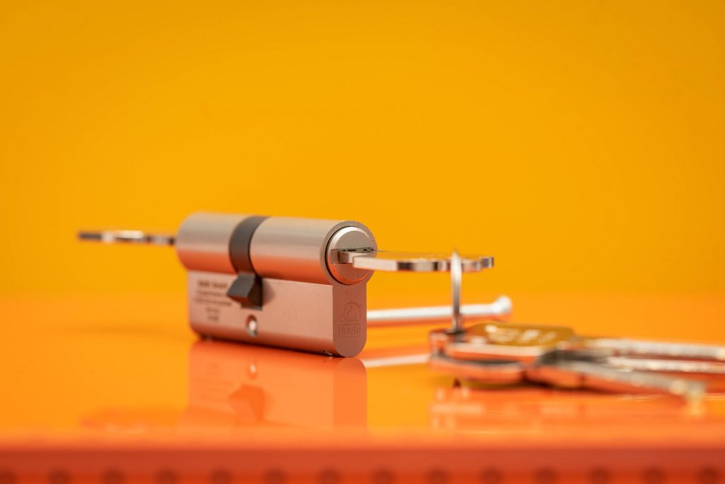 Schließzylinder mit Wendeschlüssel von BASI mit Schlüssel vor Orange- Gelben Hintergrund. Studioaufnahme.