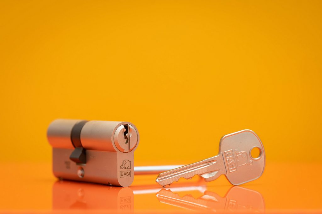 Schließzylinder von BASI mit Schlüssel vor Orange- Gelben Hintergrund. Studioaufnahme.