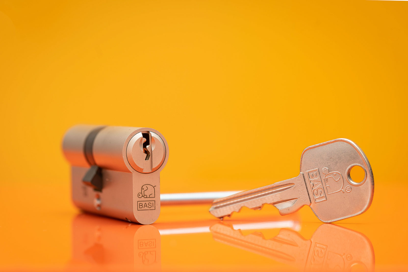 Schließzylinder von BASI mit Schlüssel vor Orange- Gelben Hintergrund. Studioaufnahme.