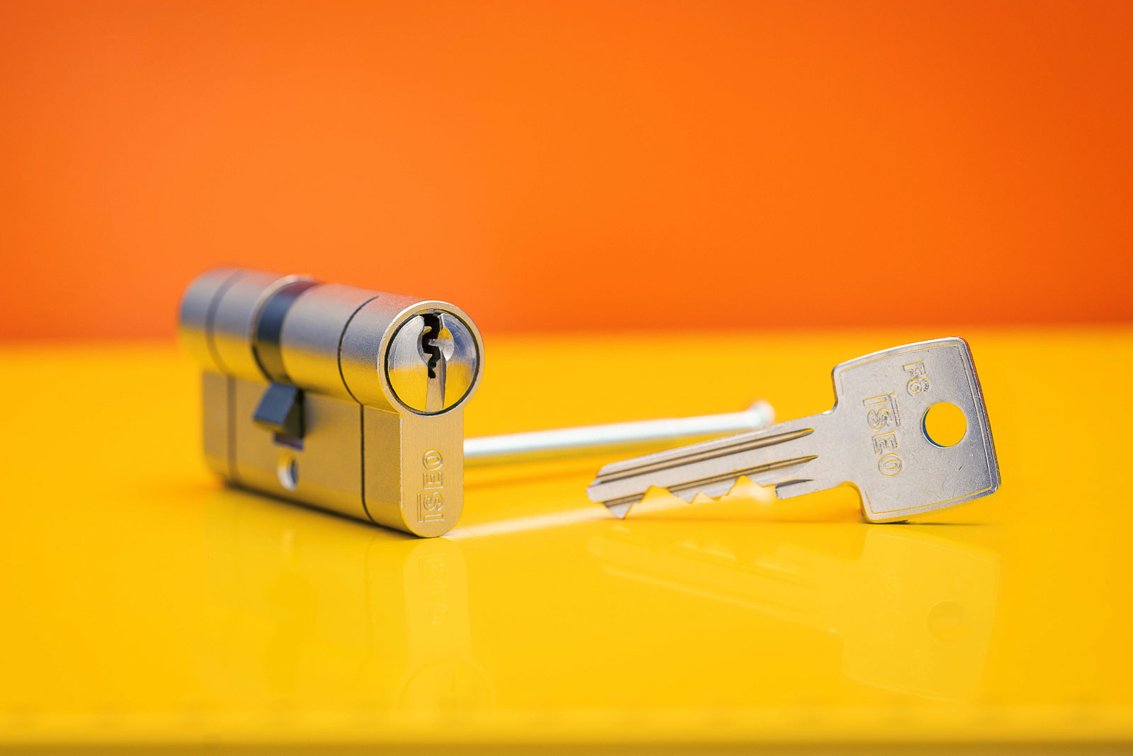 Schließzylinder von ISEO, F6 mit Schlüssel vor Orange- Gelben Hintergrund. Studioaufnahme.