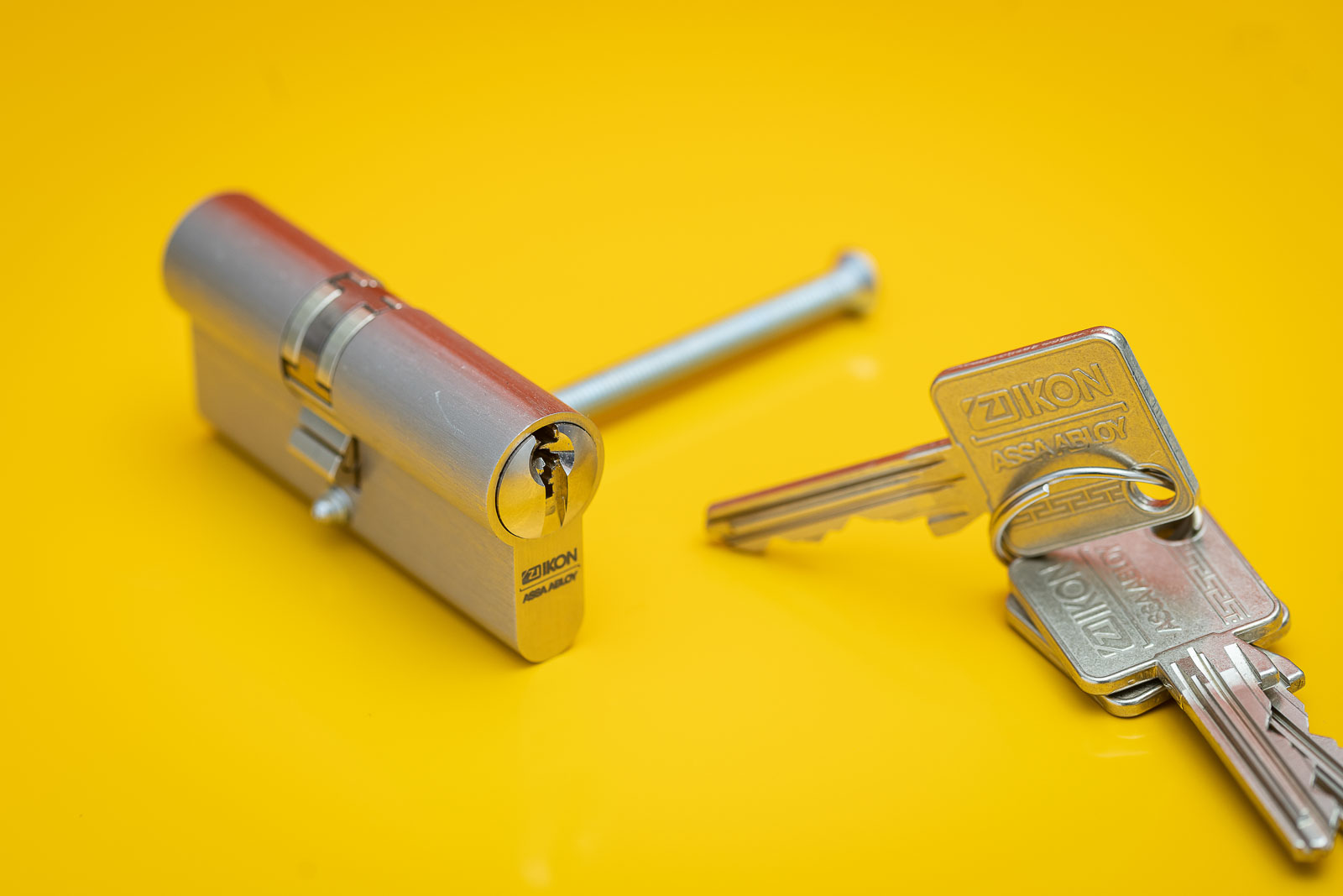 Schließzylinder von ASSA ABLOY, SK6 Sperrtechnik mit Schlüssel vor Orange- Gelben Hintergrund. Studioaufnahme.